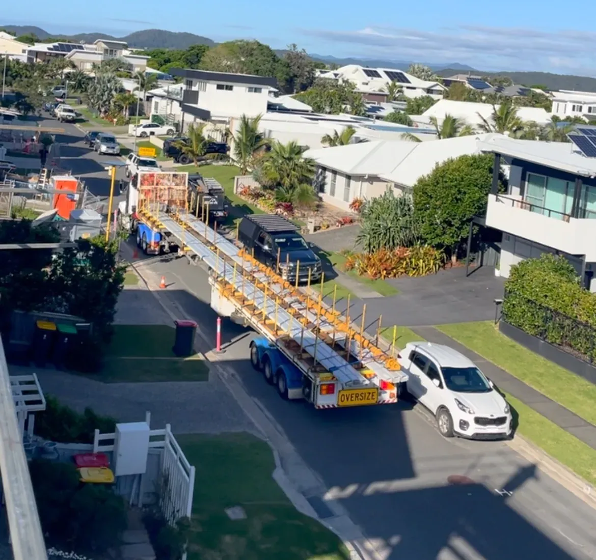 Truck delivering long clip-lock roof sheets along a residential street